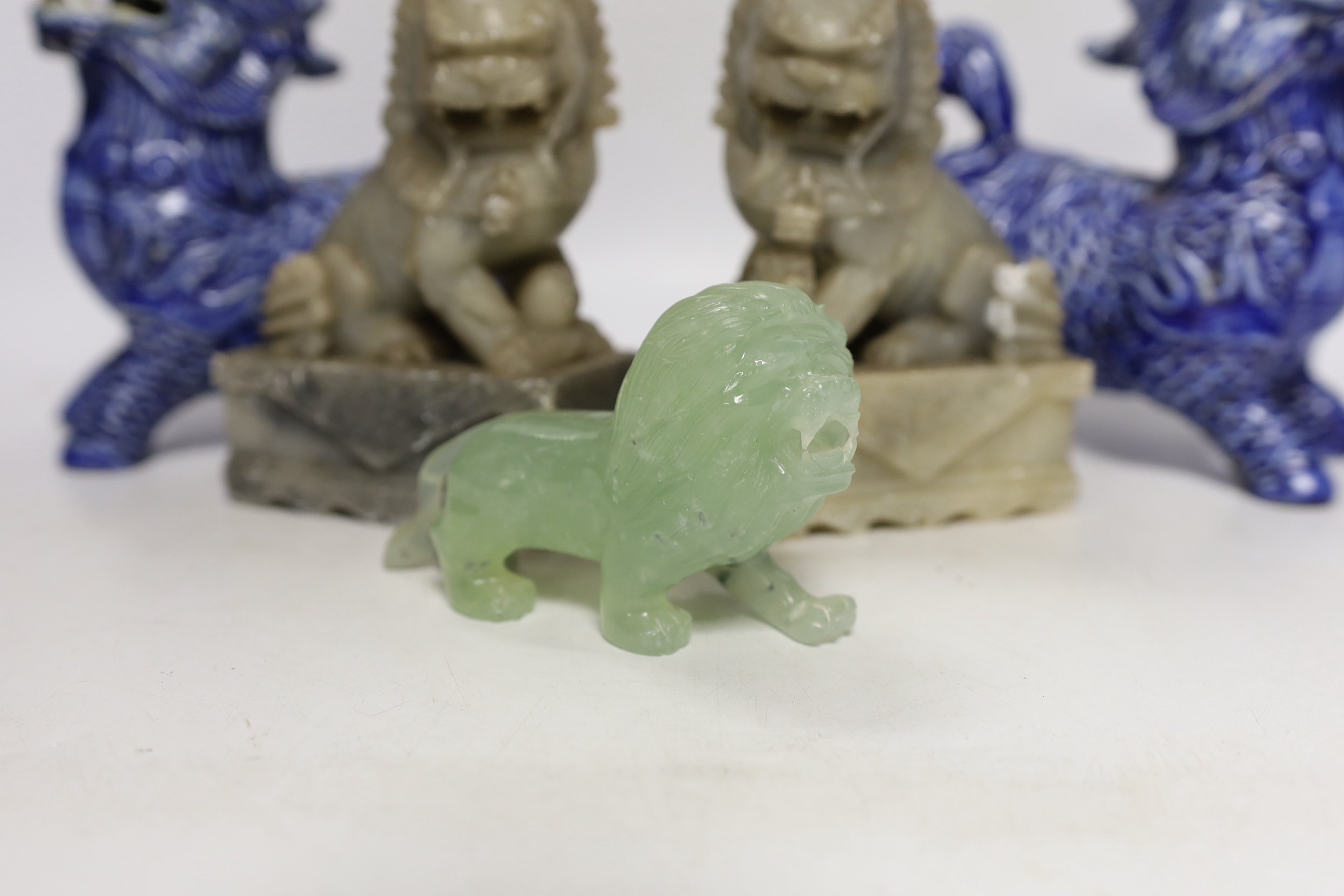 Two pairs of Chinese lion dogs; a blue and white porcelain set and a carved soapstone set, together with a carved jade lion, tallest 18cm (5)